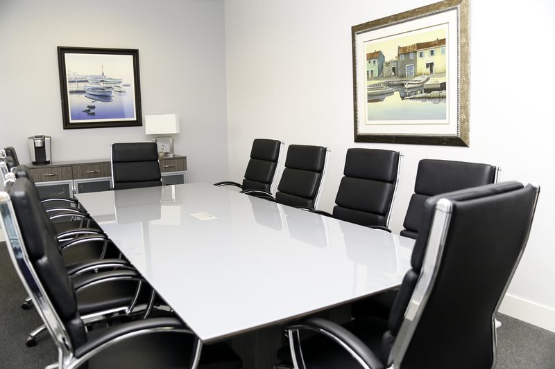 The conference room, with a long white table and black leather chairs