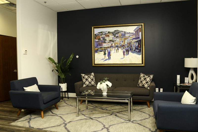 The reception lounge, with two armchairs, a sofa and a painting on a dark wall